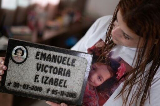 Pamela Rayane Fernandes poses holding a tombstone of her 5-year-old daughter Emanuelle, who died in Bento Rodriguez following the collapse of the Fundão dam in Cachoeira do Brumado, district of Mariana, state of Minas Gerais, Brazil, on October 9, 2024....